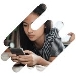 a teen girl sits on her couch looking at her phone